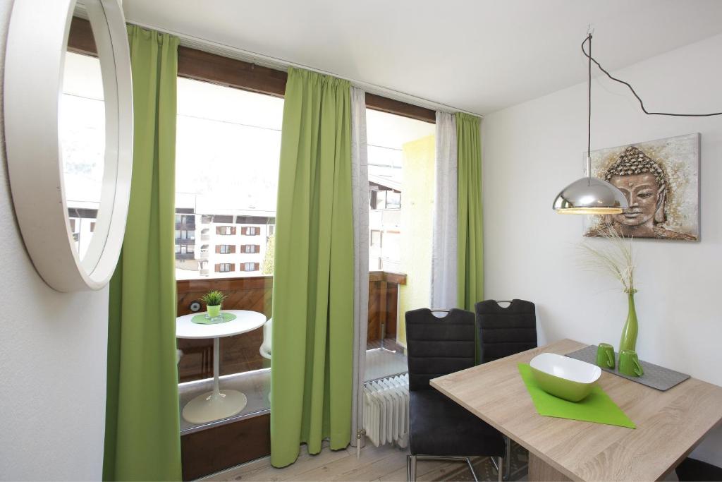 ein Esszimmer mit grünen Vorhängen und einem Tisch in der Unterkunft Apartment Domizil Maria in Kaprun