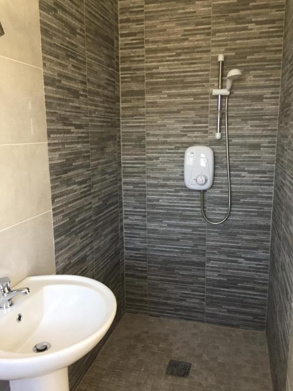 uma casa de banho com um lavatório e um chuveiro em Seafield House em Quilty