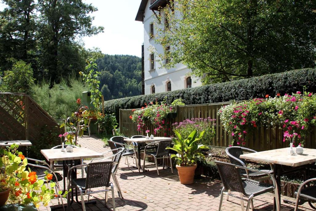een patio met tafels, stoelen en bloemen bij Hotel-Garni Elbgarten Bad Schandau in Bad Schandau
