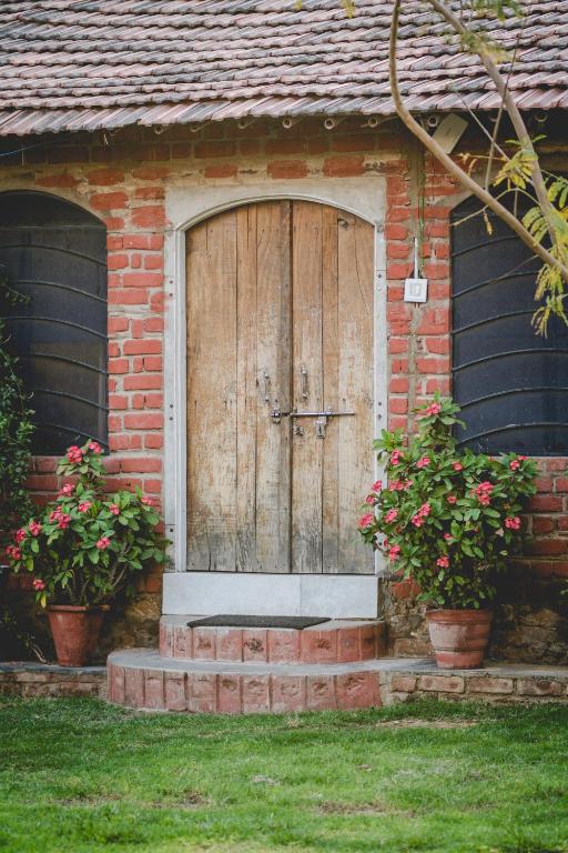 a wooden door on a brick house with two potted plants at Shannu's Ranch Inn in Pushkar