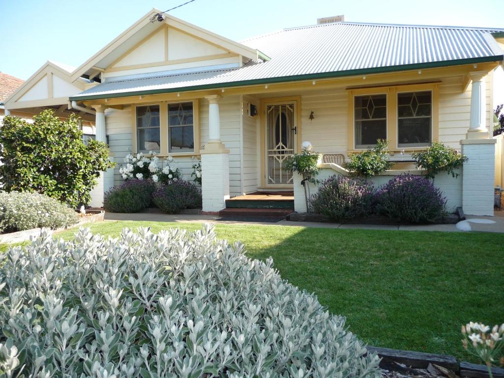 a white house with a lawn and flowers at Shepp Central Apartment in Shepparton