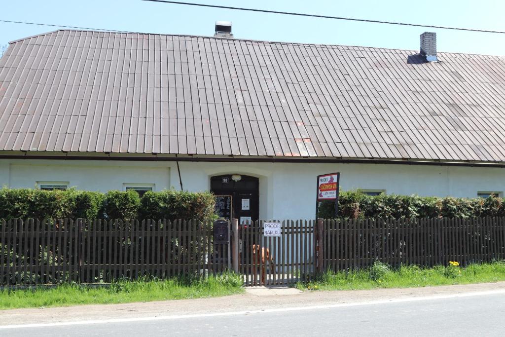 a house with a dog in front of a fence at Apartmán Nelinka in Rudná pod Pradědem