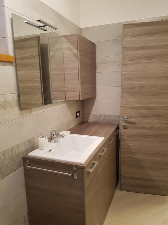 W łazience znajduje się biała umywalka i drewniane szafki. w obiekcie BMP APARTMENT DELUXE 2 JACUZZI RISCALDATA PRIVATA vista Lago di Garda w Brenzone sul Garda