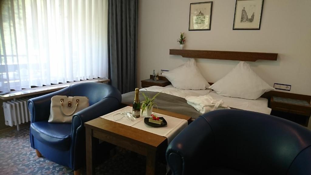 um quarto de hotel com uma cama e duas cadeiras e uma mesa em Café Blaich - Hotel Garni em Höfen an der Enz