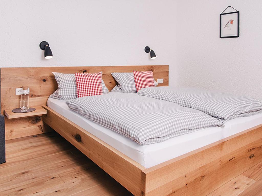 a bedroom with a wooden bed with red and white pillows at Goldvogel Apartments in Fischen