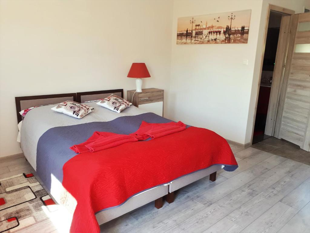 ein Schlafzimmer mit einem Bett mit einer roten Decke darauf in der Unterkunft Pensjonat pod Dębami in Świnoujście