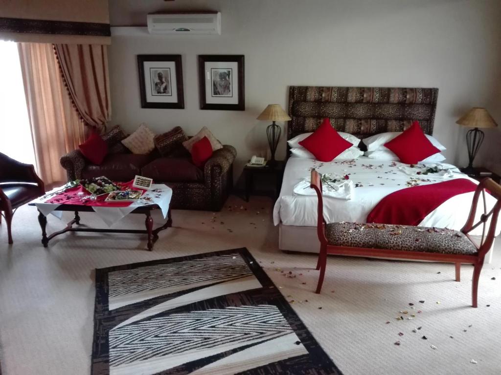 a bedroom with a bed and a couch and a table at Vido Lodge and Conference Centre in Polokwane