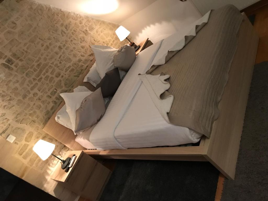 Schlafzimmer mit einem Bett mit weißer Bettwäsche und Kissen in der Unterkunft Chambre Centre Ville de Bayeux in Bayeux