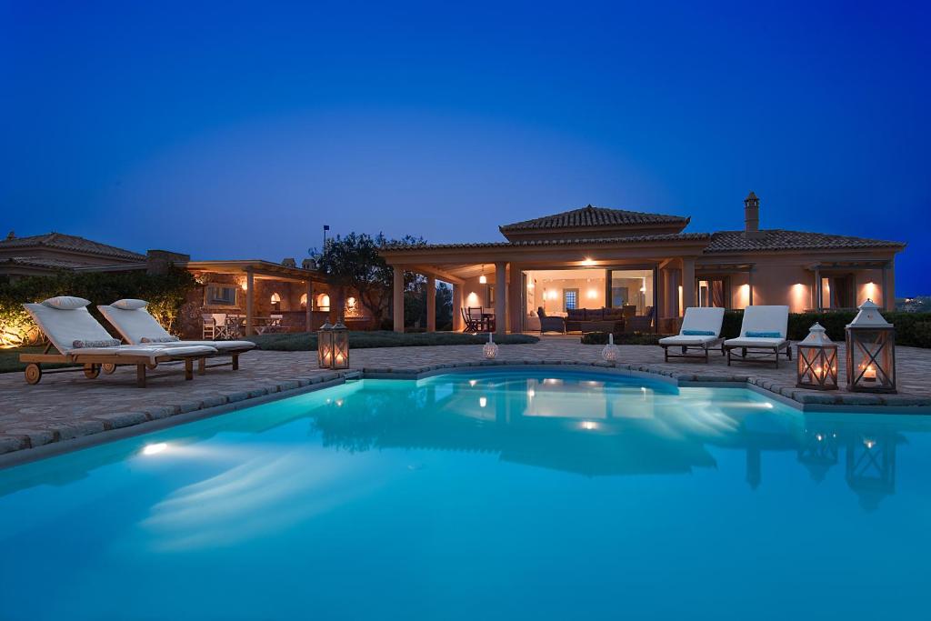 a swimming pool in front of a house at night at Villa Emerald in Porto Heli
