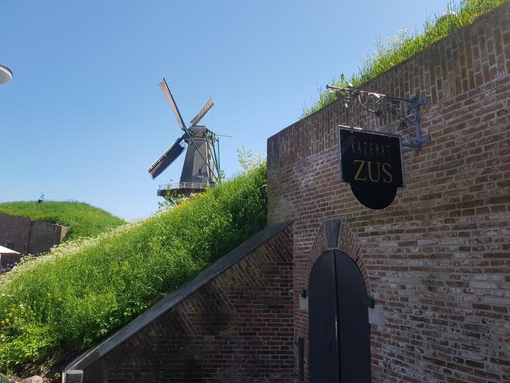 a sign on a brick building with a windmill at Kazemat Zus in Woudrichem