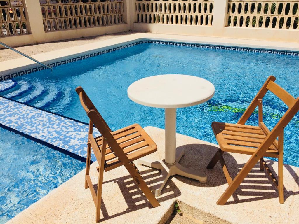 einen Tisch und zwei Stühle neben einem Pool in der Unterkunft Inlesa Vistas Al Mar in Benidorm