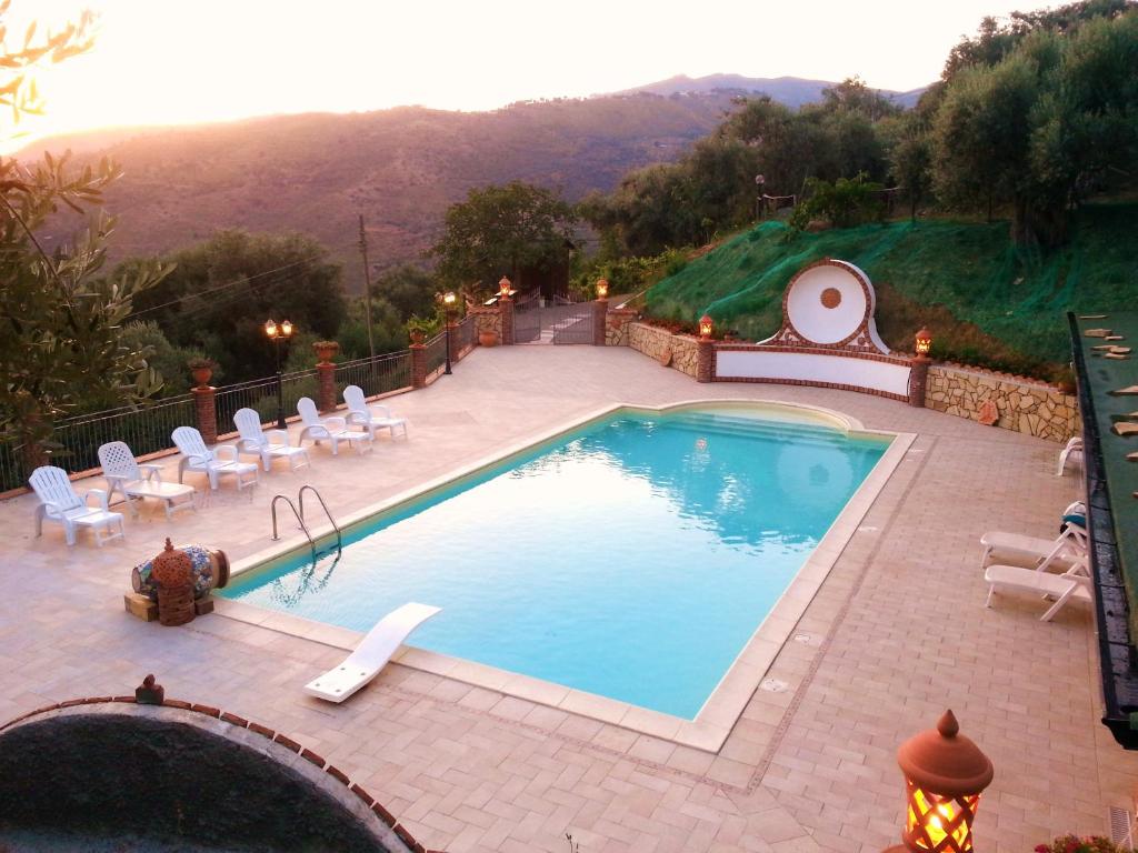 a swimming pool with chairs and a mountain in the background at L'Uliveto in Reitano