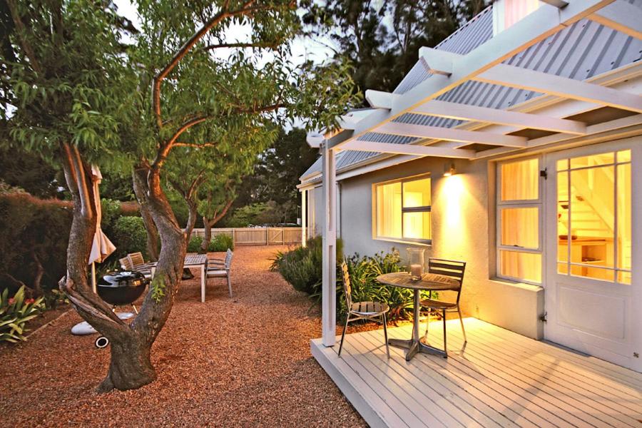 a porch of a house with a table and a tree at Almondbury Cottage in Tokai