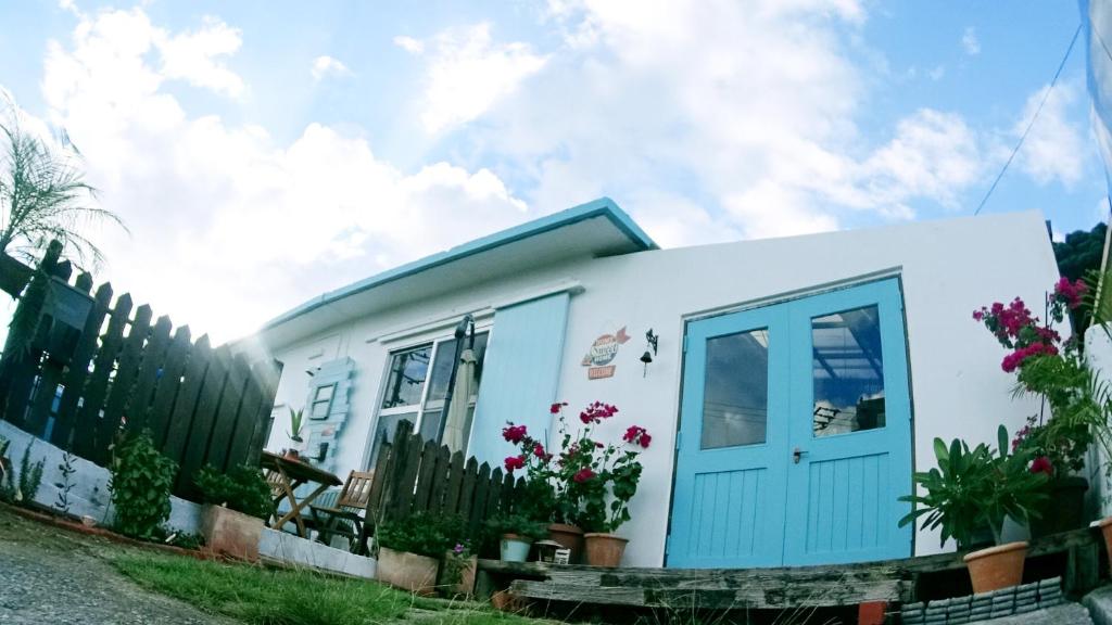 una pequeña casa con una puerta azul en Okinawan. Sweet Home. T-8, en Chatan