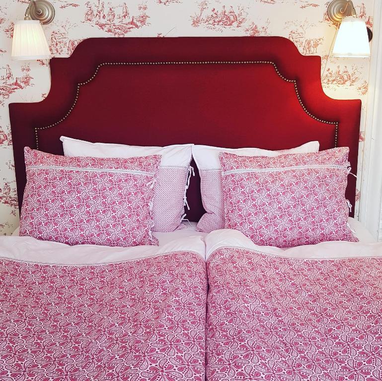 ein Bett mit rosa und weißen Kissen darauf in der Unterkunft Hem till Gården boutique hotel in Västerås
