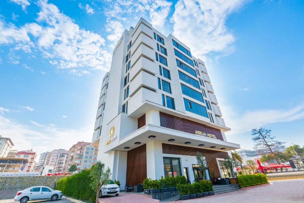 فندق Aselia Trabzon في طرابزون: مبنى أبيض طويل وبه سيارة متوقفة أمامه