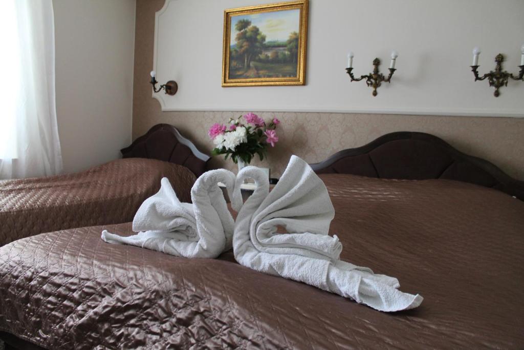 two towelsrendered to look like swans on a bed at Royal Family in Niš