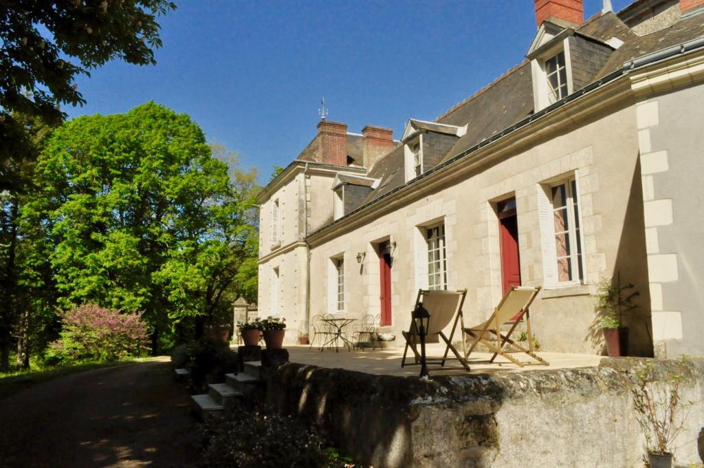 ein Haus mit Stühlen außerhalb des Hauses in der Unterkunft La Jagée in Cheillé