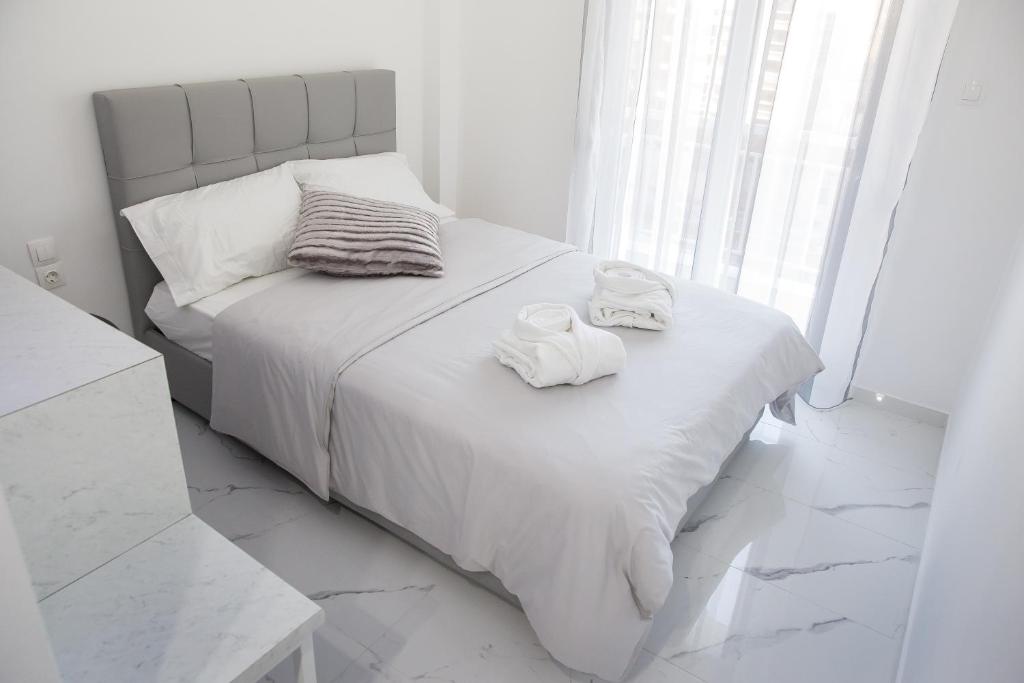 a white bedroom with a bed with towels on it at Petite Palace Aristotelous 7 in Thessaloniki