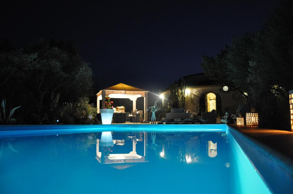 - une piscine bleue la nuit avec un kiosque dans l'établissement Villa DESIDERIA B&B, à Capitana