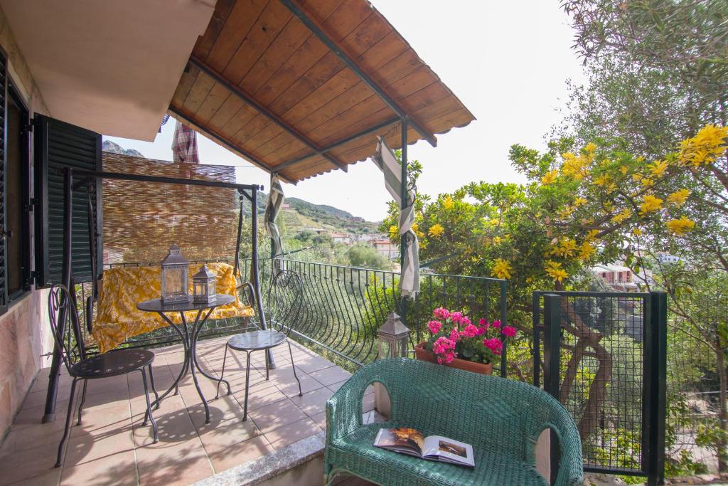 Un balcón con una silla y una mesa con flores. en Appartamento a 10 minuti a piedi dal mare, en Santa Maria Navarrese