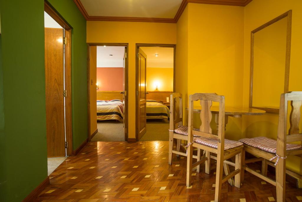 um quarto com paredes amarelas e verdes e uma mesa e cadeiras em Hotel Cima Argentum em Potosí