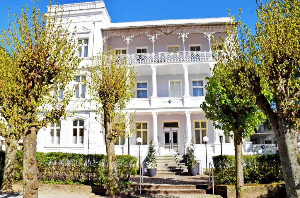 une maison blanche avec des arbres devant elle dans l'établissement Appartementhaus Sellin, à Sellin