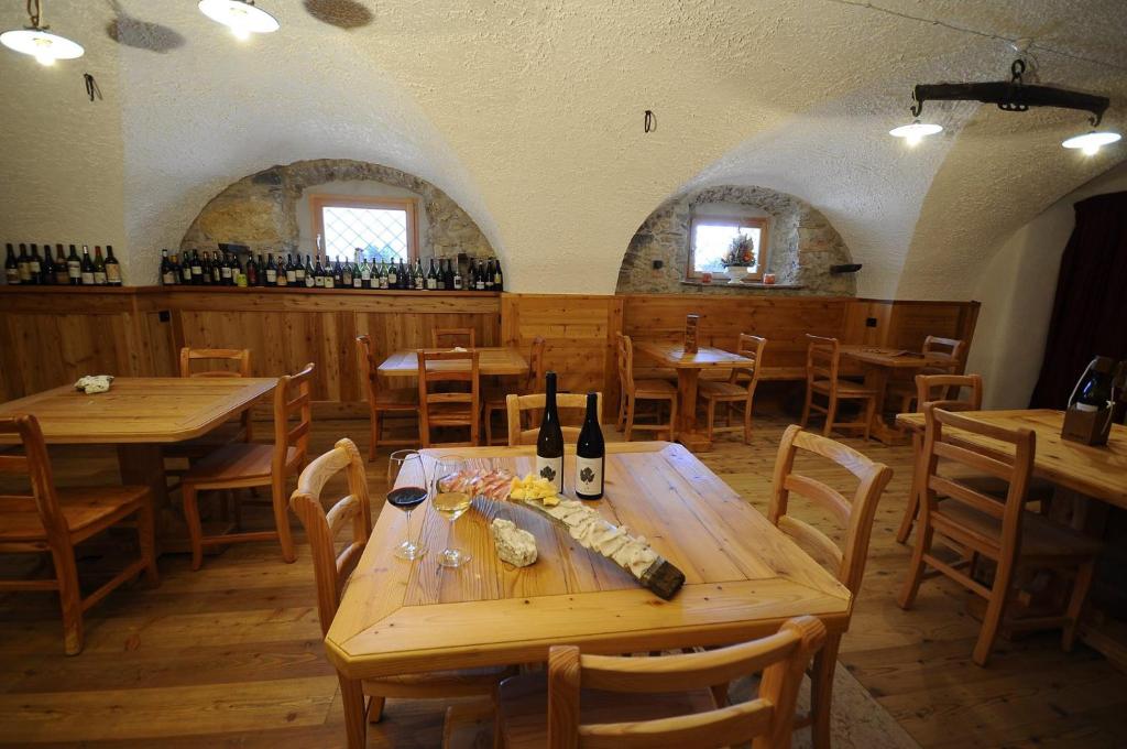 un restaurante con mesas de madera, sillas y botellas de vino en Agriturismo Eredi di Cobelli Aldo, en Lavis