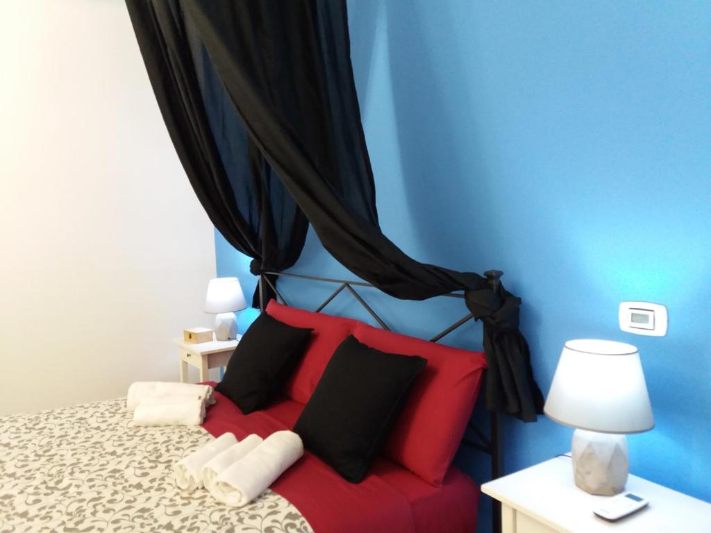 1 dormitorio con cama roja y cortinas negras en Vento d'Estate, en Trieste