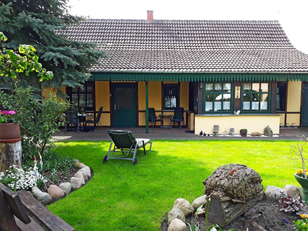 a house with a green yard with a chair in it at Pension Zum weißen Hirsch in Reitwein