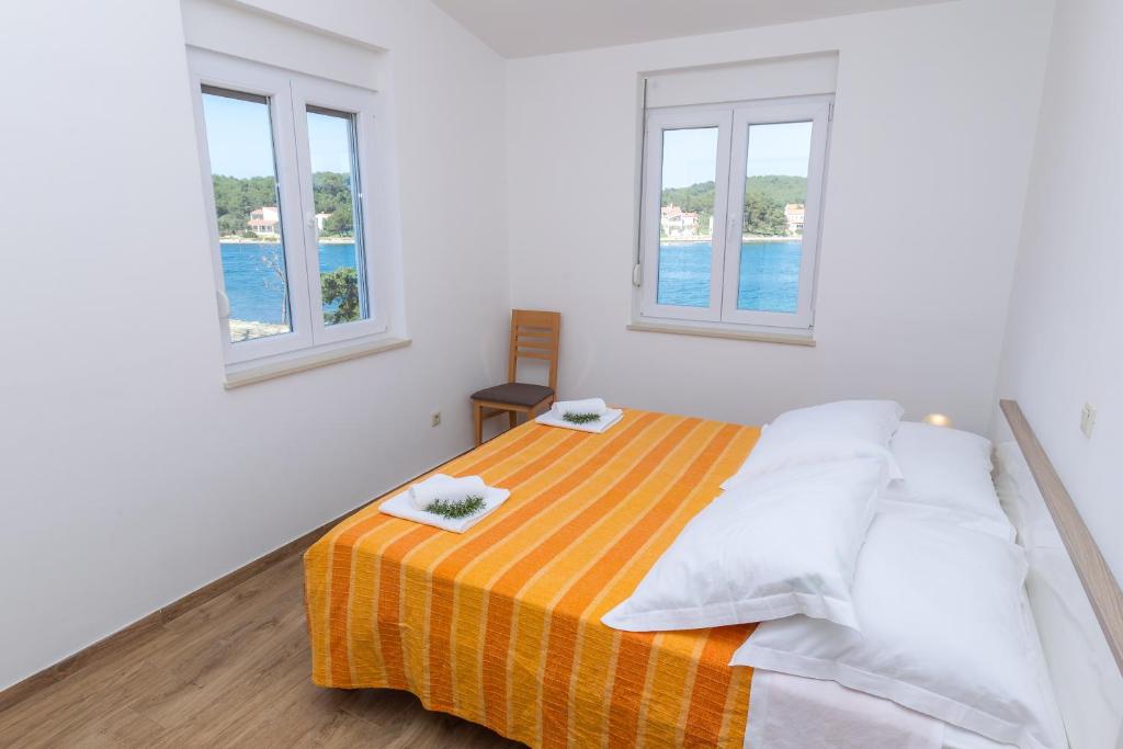 a bedroom with a bed with two windows at Apartments Medini in Veli Rat