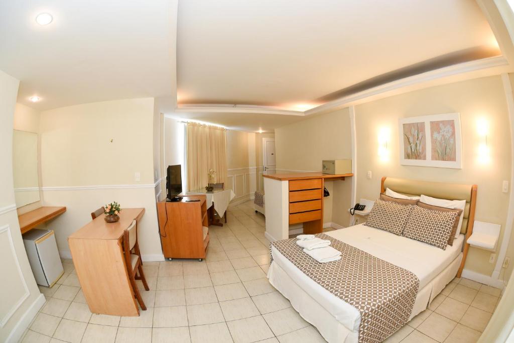 a bedroom with a bed and a desk in it at Hotel Village Icaraí in Niterói