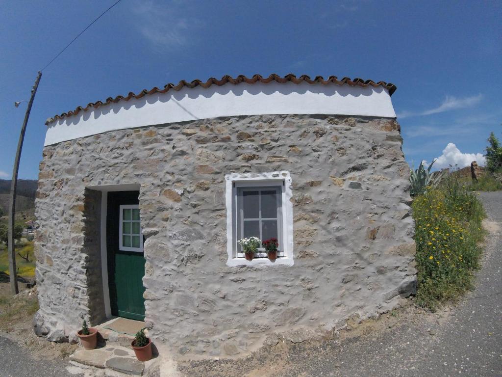 a small stone building with a window and a door at Palheiros da Ribeira in Pracana Cimeira