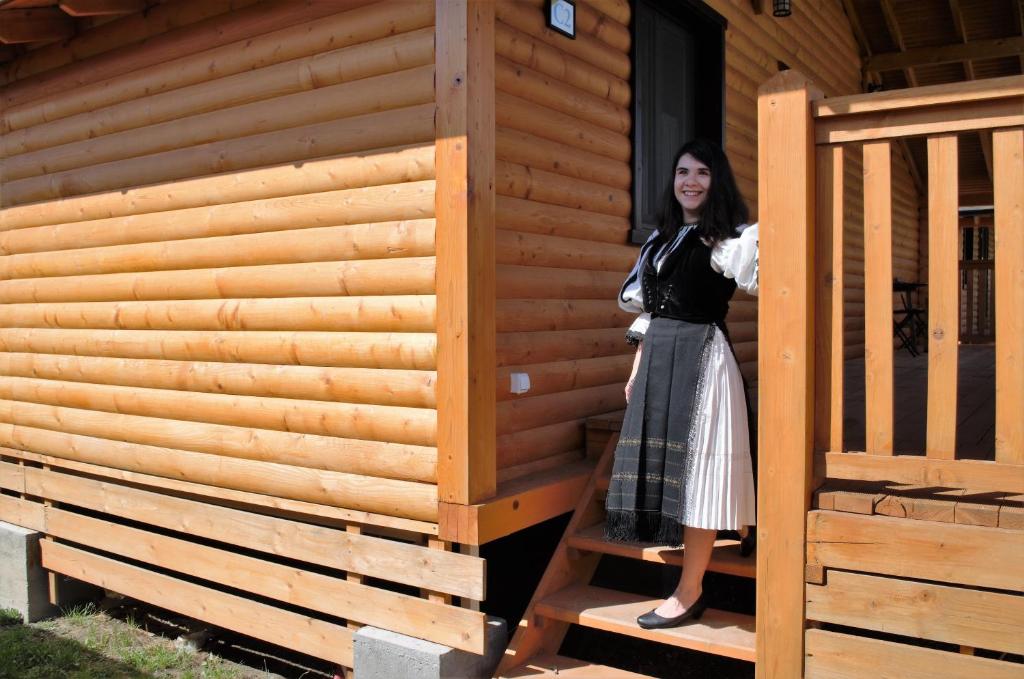 a woman standing on the stairs of a cabin at Complex Agroturistic Livada de Nuci in Baia de Fier