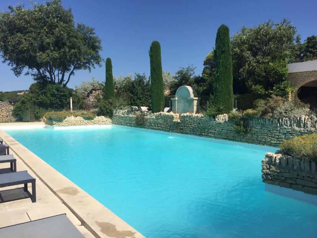 una piscina en un patio con una pared de piedra en Bastidon la Cicada, en Gordes