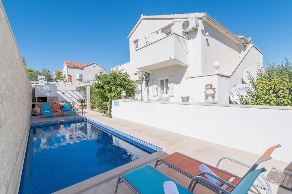 a swimming pool with chairs next to a house at Apartments Petranic in Supetar