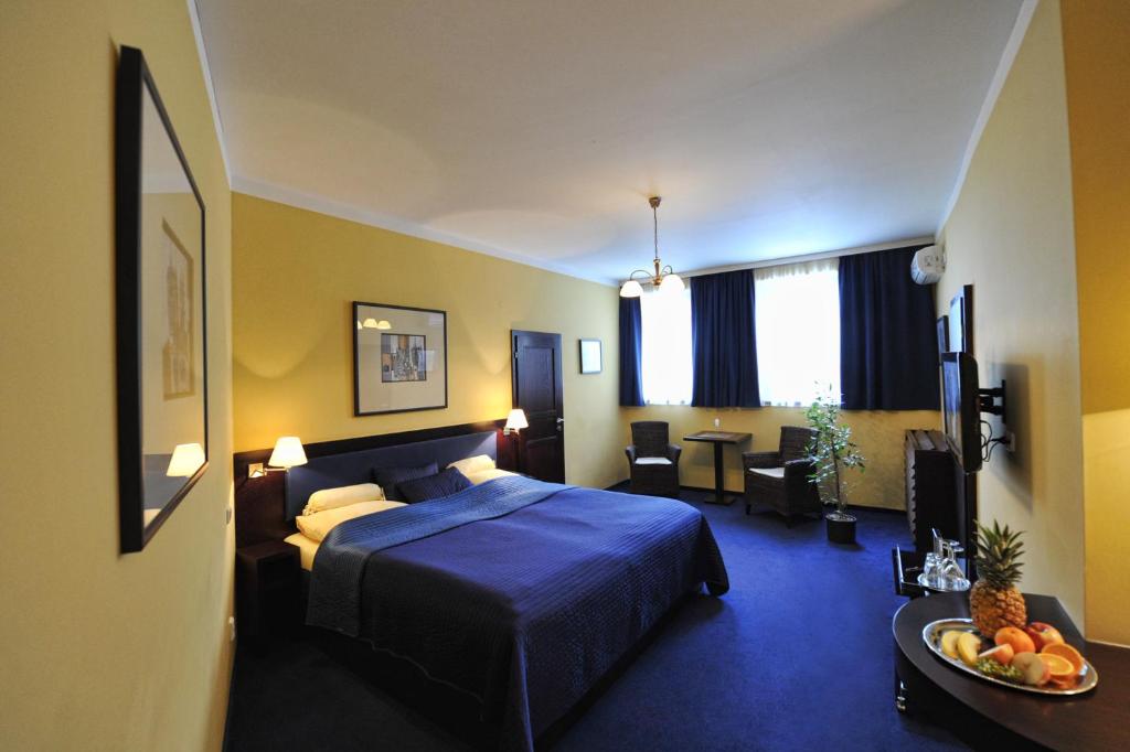 ブルノにあるホテル アルテのベッドとリビングルームが備わるホテルルームです。