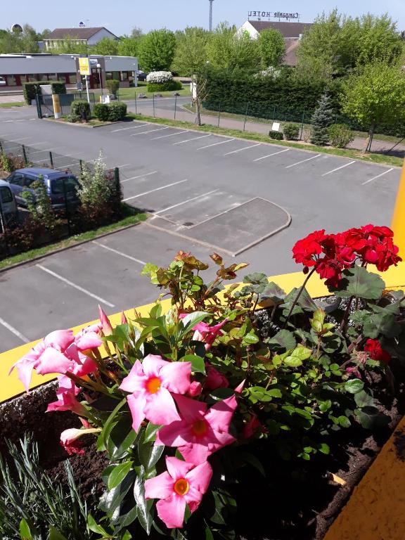 a bunch of flowers in a flower box in front of a parking lot at Premiere Classe Orleans Ouest - La Chapelle St Mesmin in La Chapelle-Saint-Mesmin