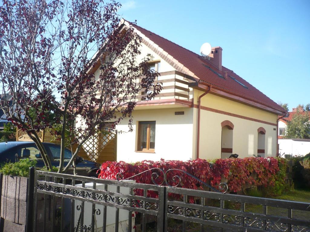 a white house with red flowers in front of it at bliźniak-apartamenty in Rowy