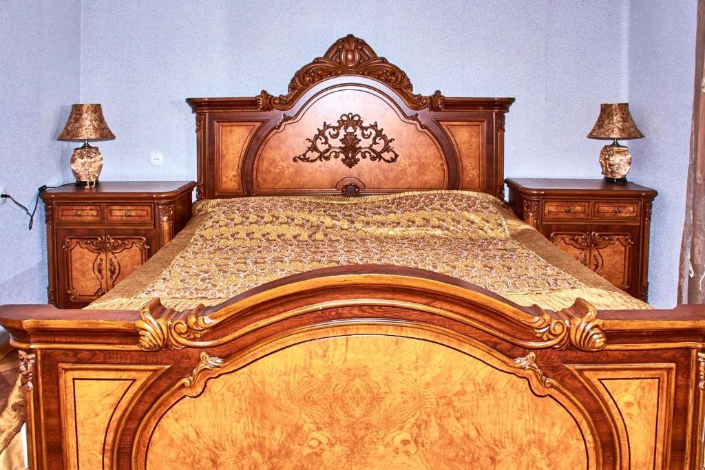 - un grand lit en bois dans une chambre avec deux lampes dans l'établissement Guest House Svetlana, à Gori