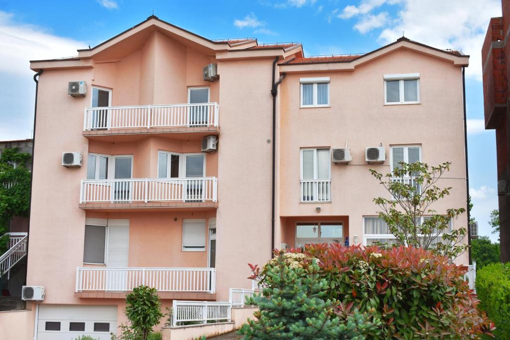 un edificio rosa con balcones y árboles en Guest House Regina Mundi, en Međugorje