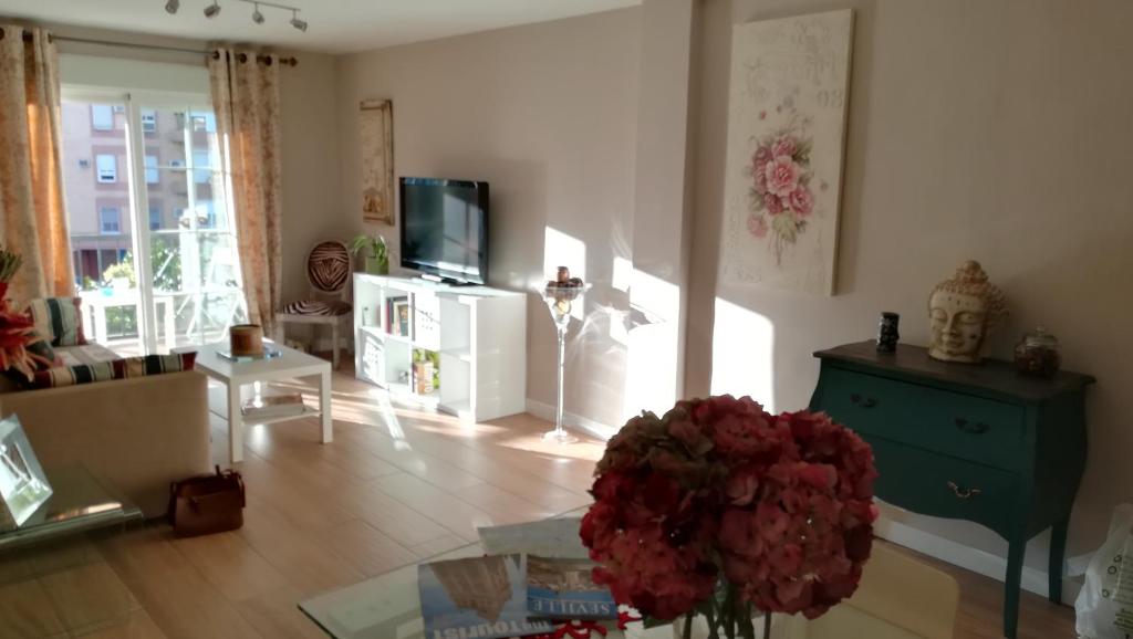 una sala de estar con un jarrón de flores sobre una mesa en Torneo FREE PARKING luminoso climatizado 7 PAX en Sevilla