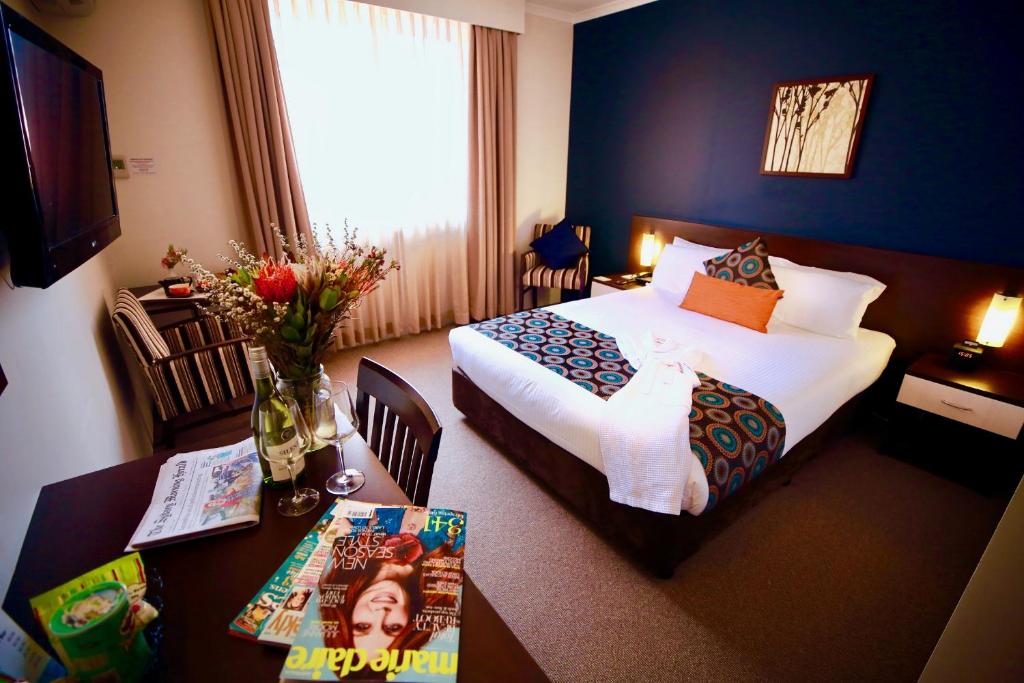 a hotel room with two beds and a table with a tableablish at 175 Hotel Westmead in Sydney