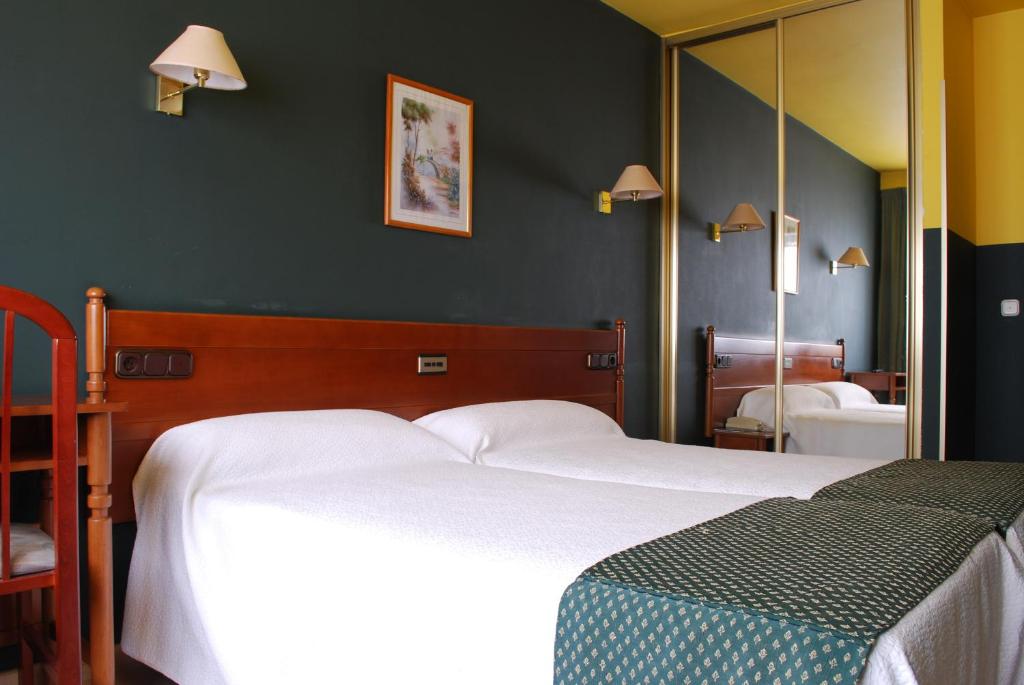 a bedroom with two beds and a mirror at Hotel San Jacobo in Santiago de Compostela