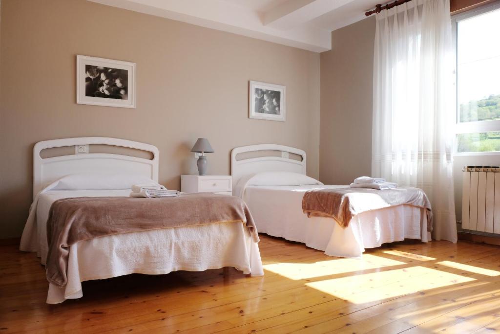 Un dormitorio con dos camas y una ventana. en La Terraza de Picos, en Ortiguero