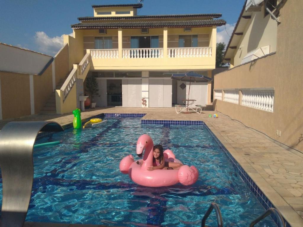 una chica en una balsa rosa en una piscina en Pousada Recanto da Fé, en Cachoeira Paulista