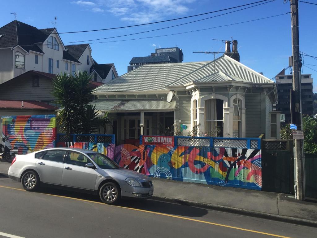 une voiture garée devant une maison avec une fresque murale dans l'établissement Worldwide Backpackers, à Wellington