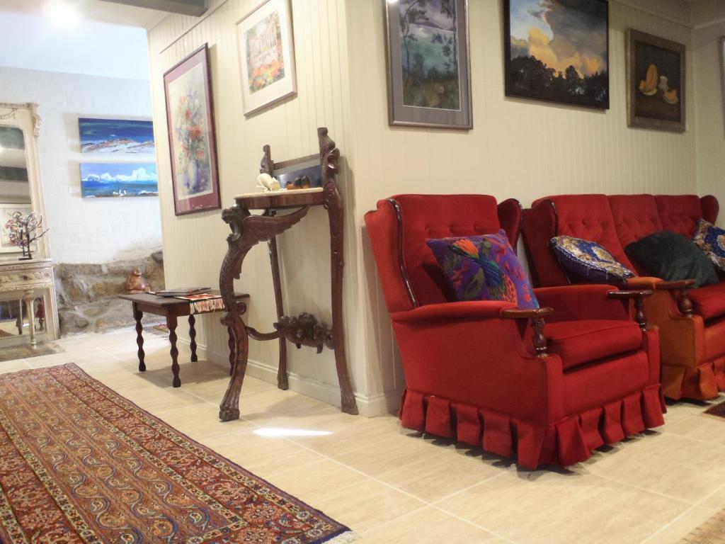 a living room with two red chairs and a table at Cosy Apartment accommodation in Hobart, New Town. in New Town