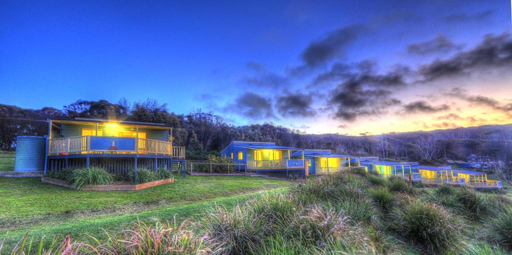 una fila de casas diminutas en un campo al atardecer en Beachcomber Holiday Park, en Potato Point