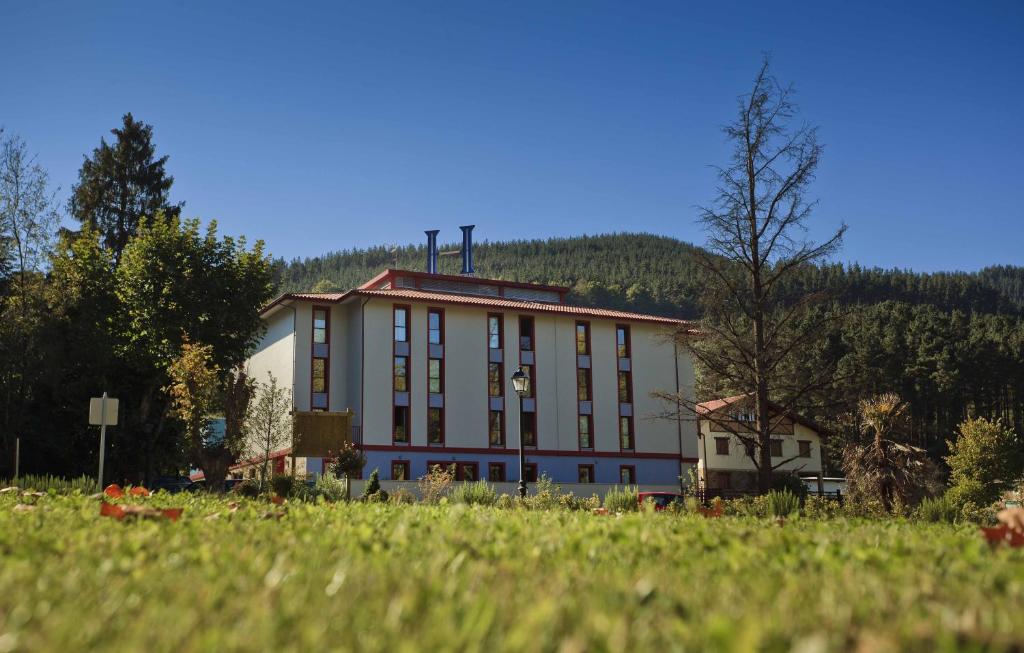 un gran edificio blanco con una colina en el fondo en Hotel Balneario Areatza Nº 01224, en Areatza